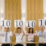 Four business people holding up score cards with 