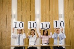 Four business people holding up score cards with "10" on them